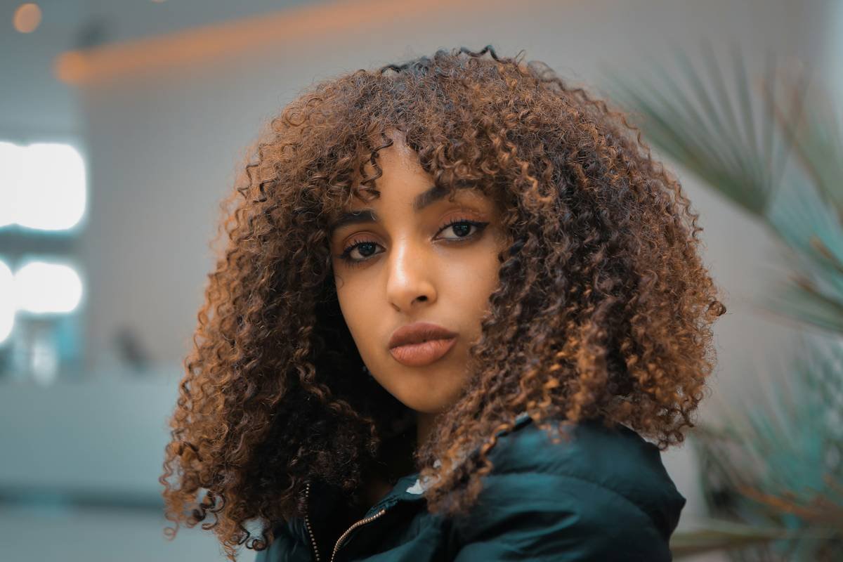 Client showcasing natural-looking curly hair perm styles after salon treatment