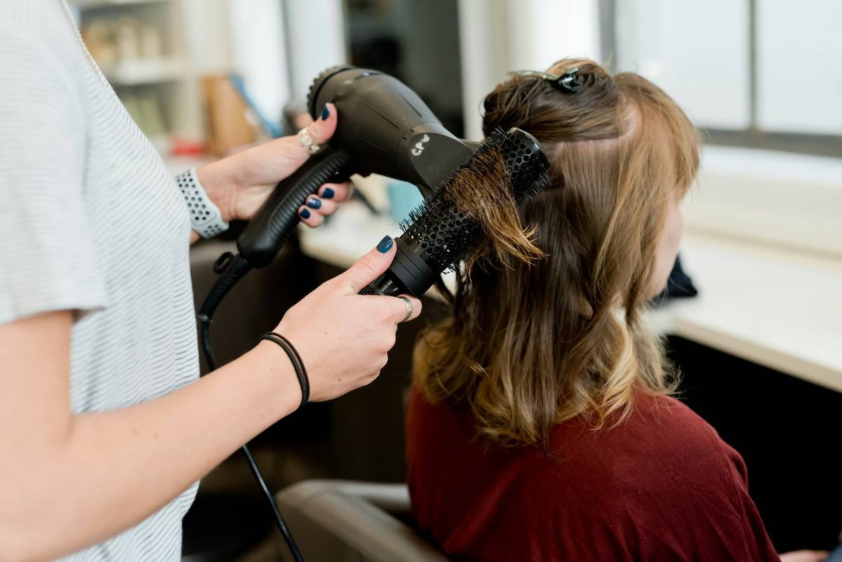 Close-up of stylist applying modern hair perm technology to sectioned hair with rods